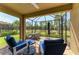 Covered patio with brick flooring, blue cushioned lounge chairs, and a screened-in view of the manicured lawn at 17696 Northwood Pl, Lakewood Ranch, FL 34202