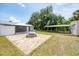 Backyard with multiple sheds, a fire pit, and a paved patio area surrounded by grassy lawn at 18348 Yale Ave, Port Charlotte, FL 33948
