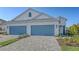 Exterior of a well lit two-story home with a light brick driveway and two-car blue garage doors at 2309 Blue Mahoe Ln, Sarasota, FL 34240