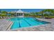 A stunning pool with blue water is surrounded by lounge chairs, palm trees, and manicured landscaping at 2309 Blue Mahoe Ln, Sarasota, FL 34240