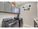 Modern laundry room featuring gray cabinets and appliances, a window, and a small accent decoration at 3110 Tolmino Ct, Bradenton, FL 34211