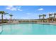 Beautiful community pool with chairs and umbrellas with a lake view under a clear blue sky at 4005 Direct Green Pl, Bradenton, FL 34208