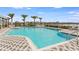 Beautiful community pool with chairs and umbrellas with a lake view under a clear blue sky at 4005 Direct Green Pl, Bradenton, FL 34208