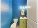 Charming powder room featuring bold blue walls, green vanity, and gold accents at 51 Webb St, Osprey, FL 34229
