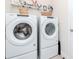 Bright laundry room features white Whirlpool washer and dryer with storage, plus shelving and decor at 5277 Grove Mill Loop, Bradenton, FL 34211