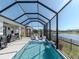 Relaxing screened pool with waterfall feature and sunny outdoor patio seating, overlooking the peaceful lake at 5277 Grove Mill Loop, Bradenton, FL 34211