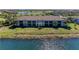 Two-story condo with a tile roof sits on a grassy lawn in front of a scenic lake at 5577 Palmer Cir # 203, Bradenton, FL 34211