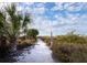 Sandy path leading to the beach, surrounded by lush greenery and palm trees on a sunny day at 640 Fox St, Longboat Key, FL 34228