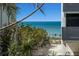Beautiful beach view through tropical vegetation with beachgoers in the distance at 6804 Gulf Dr # 6804, Holmes Beach, FL 34217