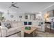 Open-concept living room featuring a large white sectional sofa, modern ceiling fan, and stylish decor at 7730 34Th W Ave # 103, Bradenton, FL 34209