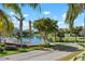 Scenic view of a tranquil pond surrounded by lush greenery and palm trees, with condos in the background under a blue sky at 7730 34Th W Ave # 103, Bradenton, FL 34209