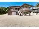 Beautiful stilted home with elevated decks, white railings, stairs, and well-maintained gravel yard at 807 S Bay Blvd, Anna Maria, FL 34216