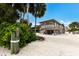 Beautiful two-story stilt home featuring a white gravel driveway, palm trees and covered balconies at 807 S Bay Blvd, Anna Maria, FL 34216