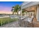 Covered balcony with seating area overlooking tranquil water view and lush tropical foliage at 810 Siesta Dr, Sarasota, FL 34242
