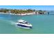 Aerial view of a sleek motor yacht cruising on clear blue waters near a scenic coastline with bridge in background at 810 Siesta Dr, Sarasota, FL 34242