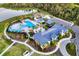 Aerial view of the community pool area, playground, parking, and clubhouse, surrounded by lush greenery at 11021 Moonsail Dr, Parrish, FL 34219