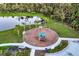 Aerial view of the playground, featuring a slide, climbing nets, and benches, with a serene pond backdrop at 11021 Moonsail Dr, Parrish, FL 34219