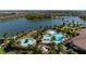 Aerial view of a resort-style pool and patio area surrounded by a lake and lush landscaping in a residential neighborhood at 11522 Trivio Ter, Palmetto, FL 34221