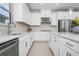 A bright, modern kitchen featuring white cabinets, stone countertops, backsplash, stainless steel appliances and sleek hardware at 11522 Trivio Ter, Palmetto, FL 34221