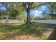 Expansive backyard with lush green grass, mature trees, and a secure white fence at 124 E 119Th Ave, Tampa, FL 33612