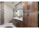 Bathroom with dark wood cabinets, quartz countertops and stylish floral wallpaper at 13635 Legends Walk Ter, Lakewood Ranch, FL 34202
