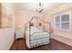Bedroom features a four poster bed frame, pink walls, dark hardwood flooring, and natural light at 13635 Legends Walk Ter, Lakewood Ranch, FL 34202
