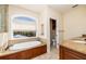 Bright bathroom with a luxurious soaking tub under a large window and granite countertops at 137 Big Pass Ln, Sarasota, FL 34242