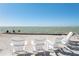 A relaxing beachfront view with four Adirondack chairs overlooking the water at 137 Big Pass Ln, Sarasota, FL 34242