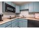 Compact kitchen featuring blue cabinets, black appliances, and efficient counter space at 137 Big Pass Ln, Sarasota, FL 34242