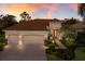Inviting home exterior showcasing a paver driveway, well-kept lawn, and warm sunset glow at 13809 Milan Ter, Lakewood Ranch, FL 34202