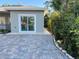 Side view of home featuring a sliding glass door, paver patio, and mature landscaping at 1534 25Th St, Sarasota, FL 34234