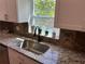 Close-up of the kitchen sink with granite countertops and window view of green trees at 1534 25Th St, Sarasota, FL 34234