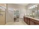 Bathroom featuring double sinks with granite countertop, wood cabinets, tile flooring and doorway to bedroom at 17440 Hampton Falls Ter, Bradenton, FL 34202