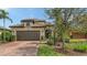 Charming home exterior with a well-maintained lawn, brick driveway, mature tree, and two-car garage in a tranquil setting at 17440 Hampton Falls Ter, Bradenton, FL 34202