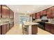 Gourmet kitchen with dark wood cabinets, granite countertops, stainless steel appliances, and a large island with seating at 17440 Hampton Falls Ter, Bradenton, FL 34202