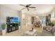 Spacious living room with tile flooring, a ceiling fan, a TV, and an open layout leading to the kitchen and dining area at 17440 Hampton Falls Ter, Bradenton, FL 34202