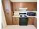 The full kitchen has tile flooring with a range, microwave, and cabinets at 182 Pineneedle Dr # 182, Bradenton, FL 34210