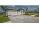 Impressive driveway with patterned brick pavers leading to a pristine three-car garage and manicured lawn at 2015 Bolsena St, Nokomis, FL 34275