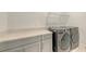 This laundry room features gray cabinets, gray countertops, a washer, and a dryer at 2015 Bolsena St, Nokomis, FL 34275