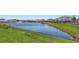 View of the pond with a fountain surrounded by green grass and other homes at 2015 Bolsena St, Nokomis, FL 34275
