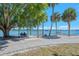 A peaceful waterfront park with a bench swing, palm trees, and serene views of boats sailing on the bay at 2105 Hibiscus St, Sarasota, FL 34239