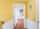 Hallway with yellow walls and white wainscoting leading to a bright, modern kitchen at 2300 Avenue B, Bradenton Beach, FL 34217