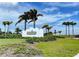 A well-manicured entrance to the Beach Club featuring lush landscaping and a clear blue sky at 315 Sapphire Lake Dr # 202, Bradenton, FL 34209