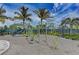 Community playground with modern play equipment, palm trees, and a secure fenced perimeter at 315 Sapphire Lake Dr # 202, Bradenton, FL 34209