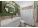 Renovated bathroom featuring a green accent wall, round mirror, and a new vanity at 3458 Lalani Blvd, Sarasota, FL 34232