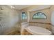 Stunning main bathroom with a tiled shower, a soaking tub, and a unique arched window that brings in natural light at 4445 Oak View Dr, Sarasota, FL 34232