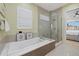 Bright bathroom with a tiled tub, glass enclosed shower, and access to the main bedroom at 4607 5Th Ne Ave, Bradenton, FL 34208