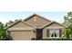 Charming single-story home with beige siding, a two-car garage, and manicured landscaping at 4611 Dusky Dawn Ln, Palmetto, FL 34221