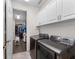 Functional laundry room with modern washer and dryer, white cabinets, and storage leading into the walk-in closet at 4611 Los Robles Ct, Palmetto, FL 34221