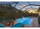 Beautiful outdoor pool area with clear blue water, lounge chairs, umbrella, and lush surroundings at sunset at 4611 Los Robles Ct, Palmetto, FL 34221
